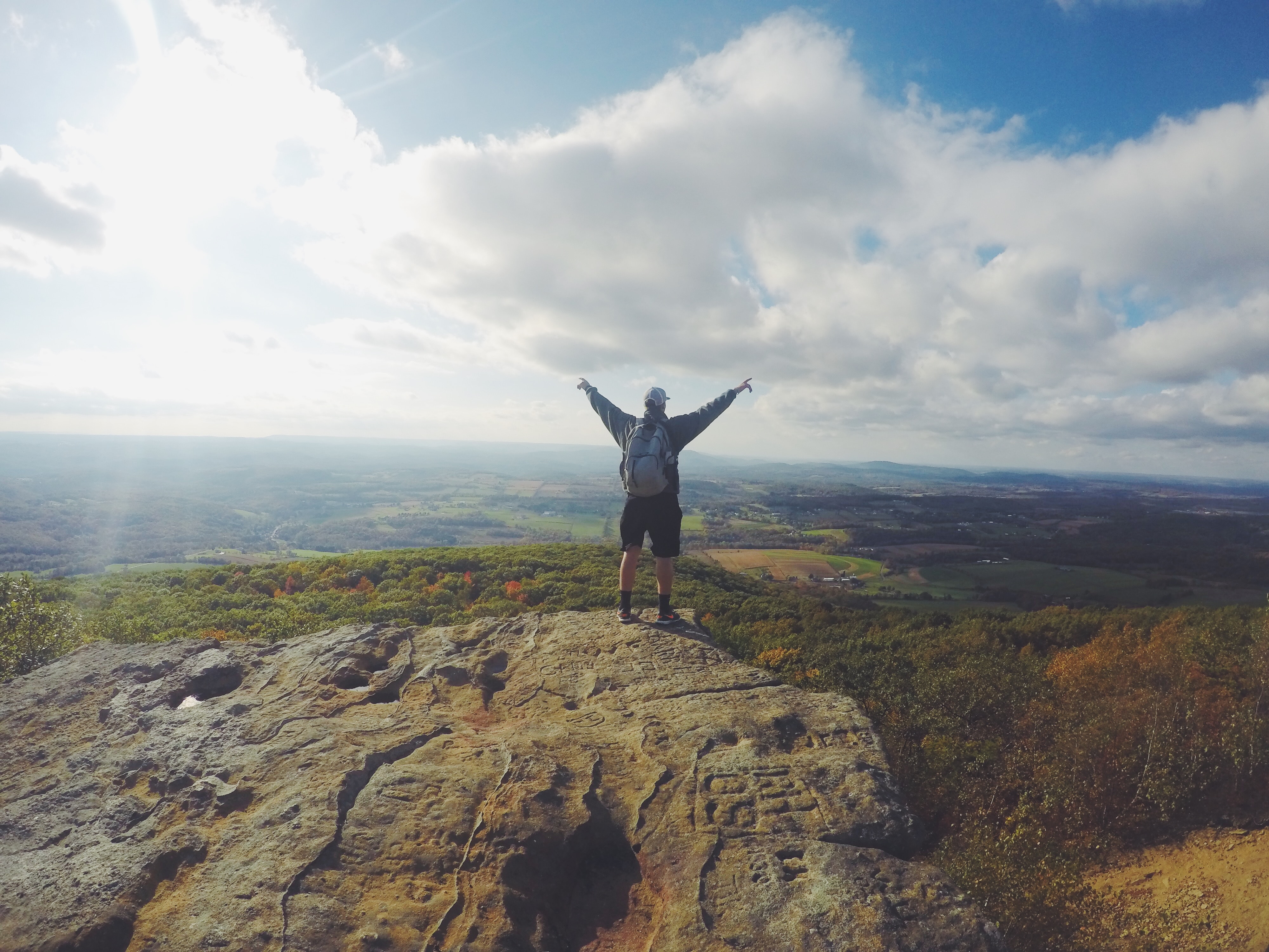 personne au bord d'une falaise les mains en l'air